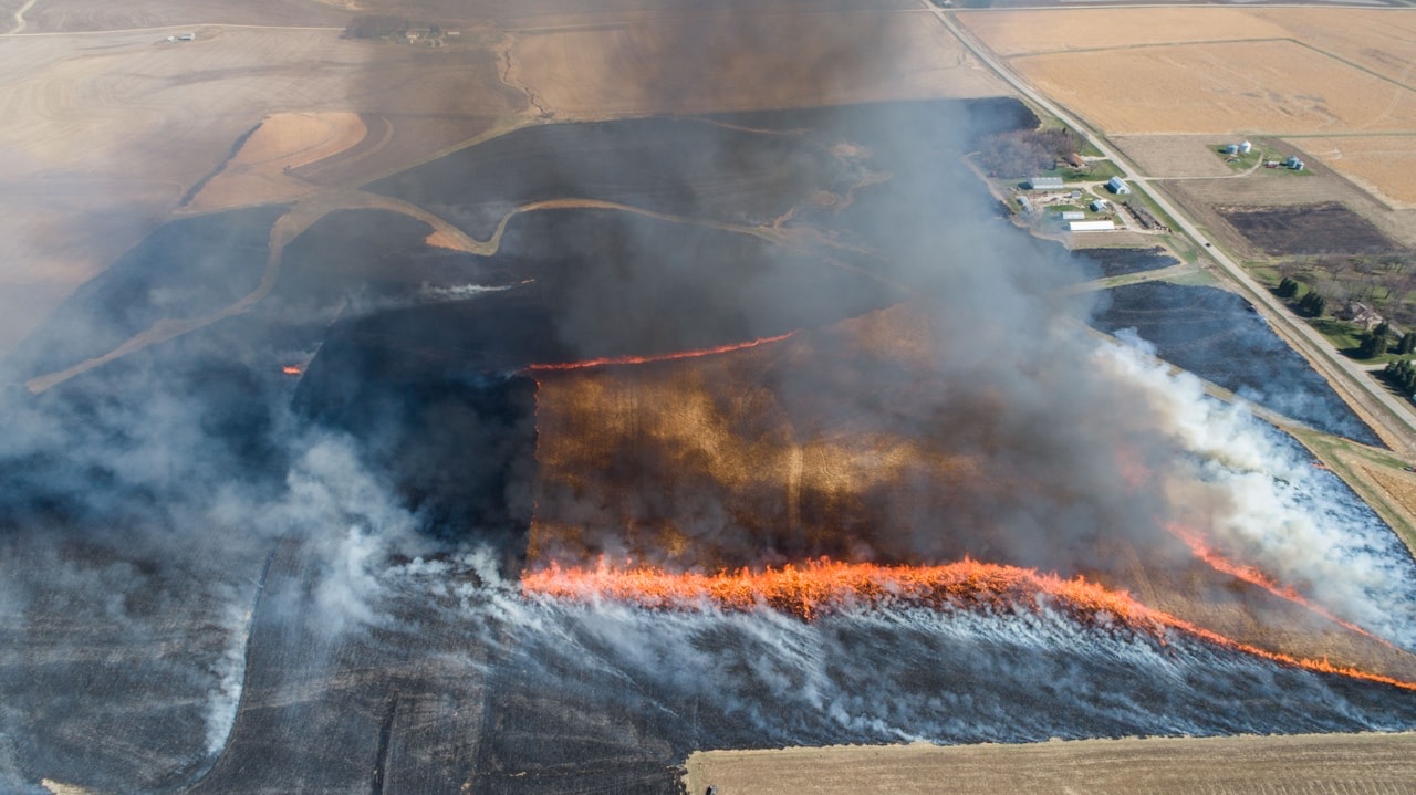 Aerial drone view of wildfire spreading across agricultural fields