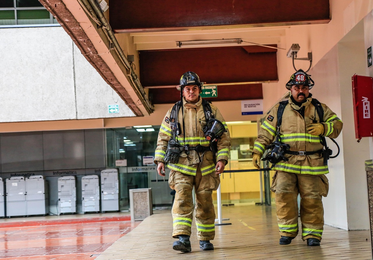 Firefighters in tan structural turnout gear with traditional helmets