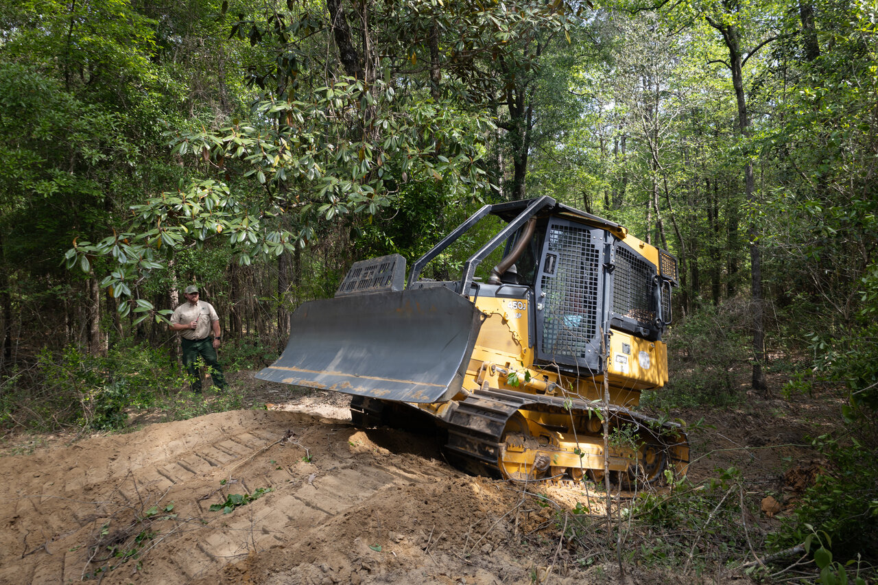 Fire bulldozer operating in a forest with dust and sunlight
