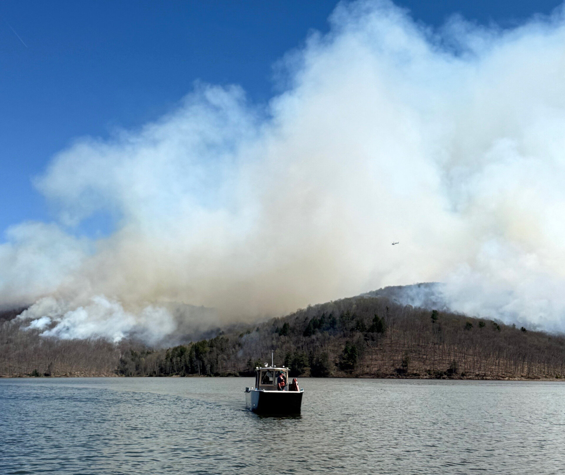 Smoke rises over the Allegheny Reservoir during the Tracy Ridge prescribed fire with a Forest Service boat patrolling the perimeter