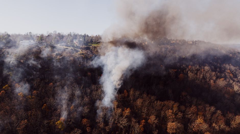 Aerial shot of smoke rising from a wildfire near residential area