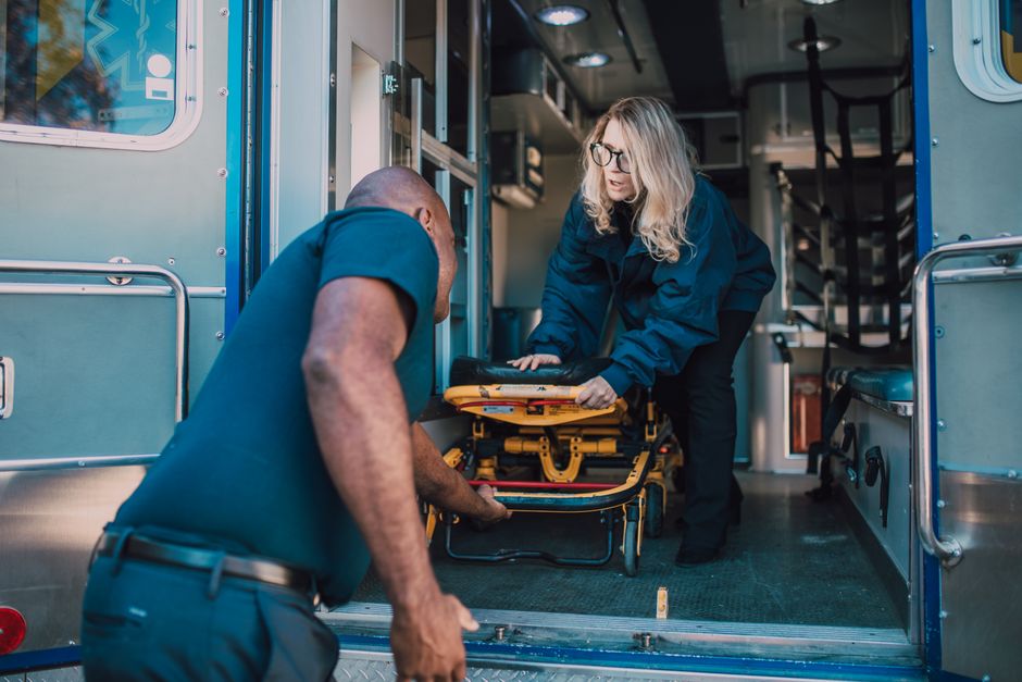 Two paramedics loading a stretcher into an ambulance during an emergency response
