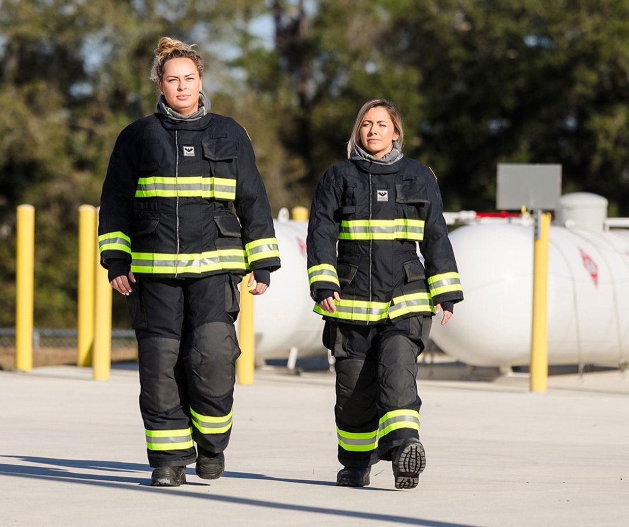 Female firefighter in full structural turnout gear and helmet at a fire scene