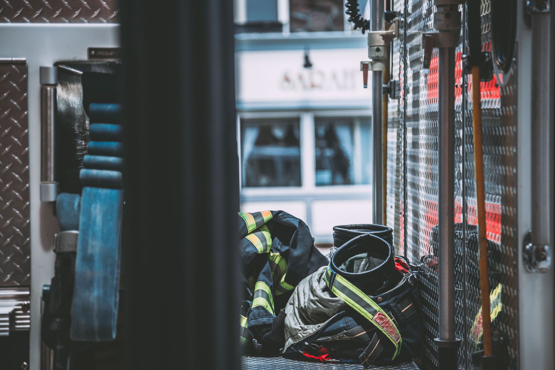 Firefighter turnout gear, coat and pants with black boots, stowed in the compartment of a fire engine