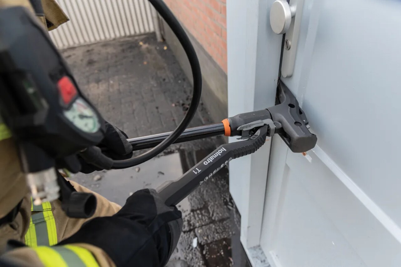 Firefighter using the Holmatro T1 hydraulic forcible entry tool to breach a metal door