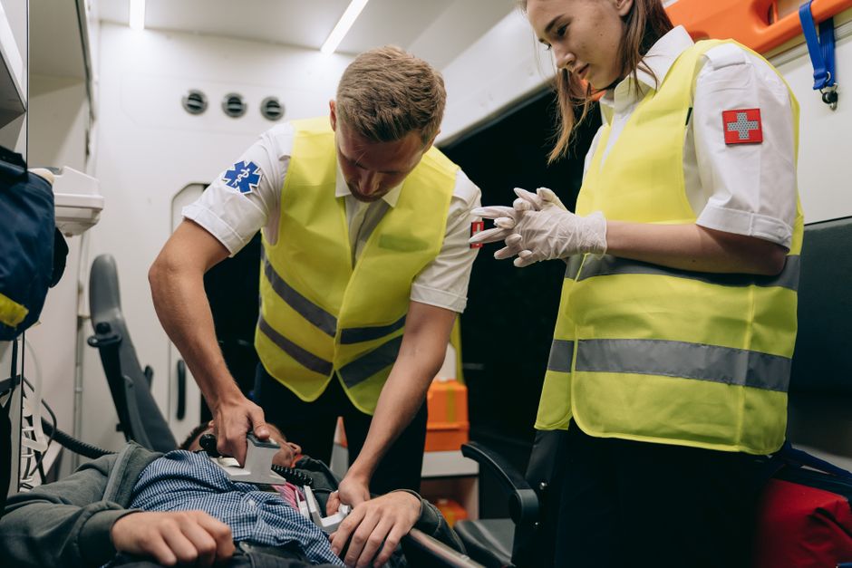Two EMS providers treating a patient inside an ambulance with a portable monitor