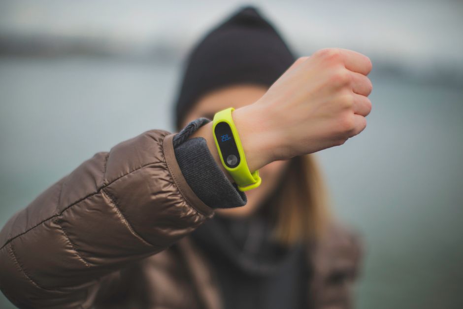 A person checking a wearable fitness tracker with a digital display on their wrist